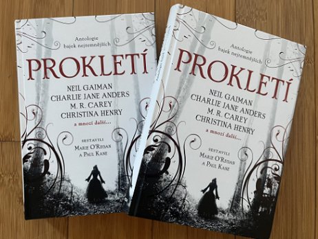 photograph of two copies of the Czech translation of Cursed, edited by Marie O'Regan and Paul Kane, lying on a wooden background