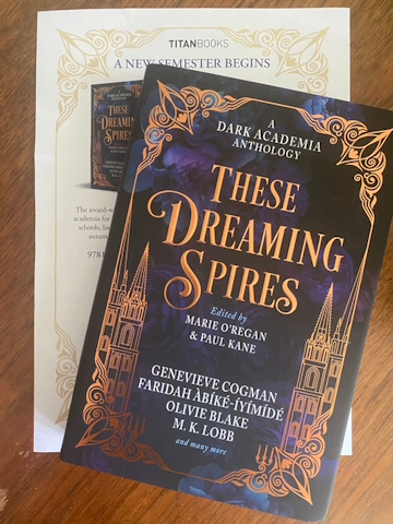 photograph showing a copy of These Dreaming Spires, edited by Marie O'Regan and Paul Kane, lying on top of the book's press release, on a wooden surface