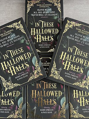 display of six copies of In These Hallowed Halls, edited by Marie O'Regan and Paul Kane, on a grey cloth surface