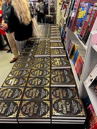 Long view from the side of a table full of copies of In These Hallowed Halls, edited by Marie O'Regan and Paul Kane