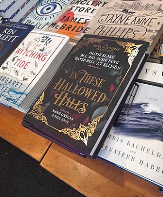 photograph of a table laid out with books, featuring In These Hallowed Halls, edited by Marie O'Regan and Paul Kane