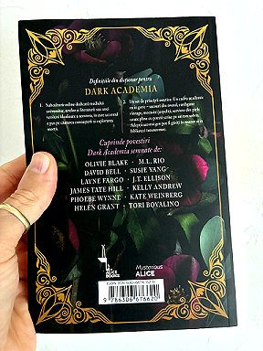 photograph showing a man's hand holding a copy of the Romanian edition of In These Hallowed Halls, edited by Marie O'Regan and Paul Kane, against a white background to show the back cover of the book