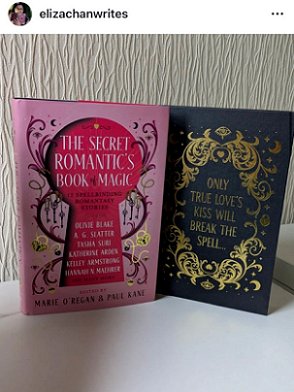 photograph of a copy of The Secret Romantic's Book of Magic, edited by Marie O'Regan and Paul Kane, standing on a white surface against a cream background. The dustjacket is standing beside the actual black cover of the book, to show the gold scrollwork around the text 'ONLY TRUE LOVE'S KISS WILL BREAK THE SPELL...