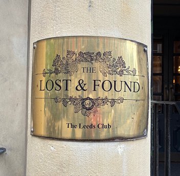 photograph showing a brass sign on a concrete column. Sign reads The Lost & Found. The Leeds Club