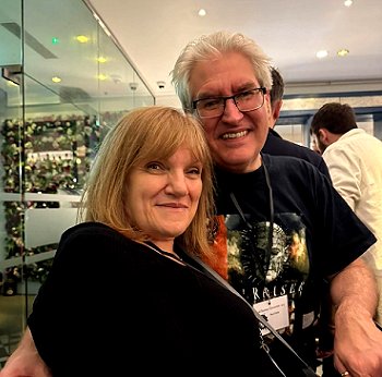 photograph showing a smiling Marie O'Regan (foreground) sitting beside a smiling Paul Kane (background)