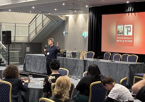 photograph of the Flame Tree Press launch at WFC2025. Photograph shows Nick Wells speaking to the audience